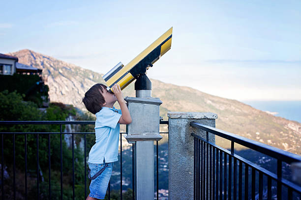 istock Curious boy, looking through a telescope at something interestin 489667624