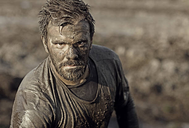 escuro pêlo homem apresentando durante uma corrida na lama - mud run imagens e fotografias de stock