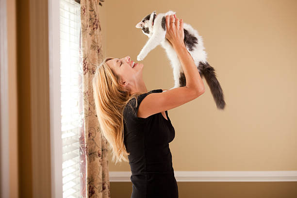 A woman smiles as she lifts a beautiful 5 month old long hair kitten.