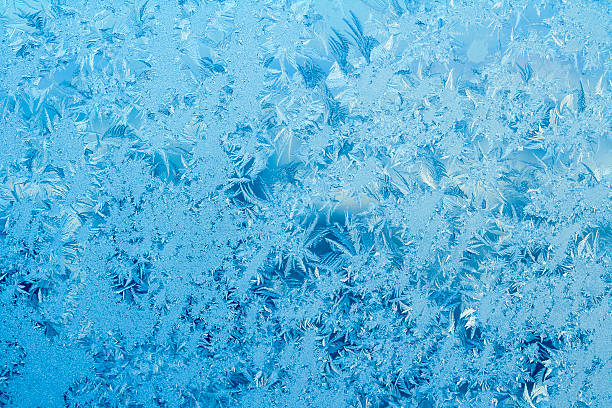 Frosty pattern on a window Beautiful frost pattern on a window in blue tones. Can be used as a winter / holiday background. ice crystal blue frozen cold stock pictures, royalty-free photos & images