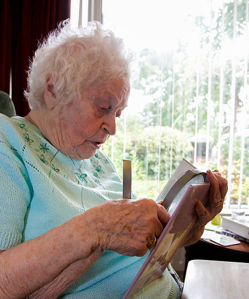 istock Elderly woman using a magnifier to read a book 489696520