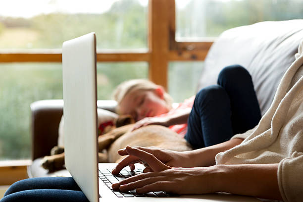 Mother using laptop whilst daughter sleeps