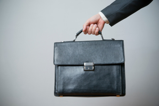 Businessman with briefcase in hand on gray background