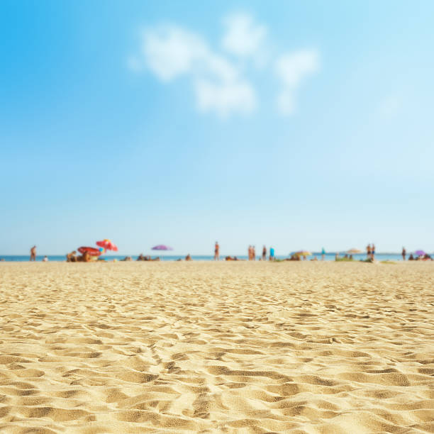 sand on the beach with blurred sea and peoples, sky with clouds. soft focus