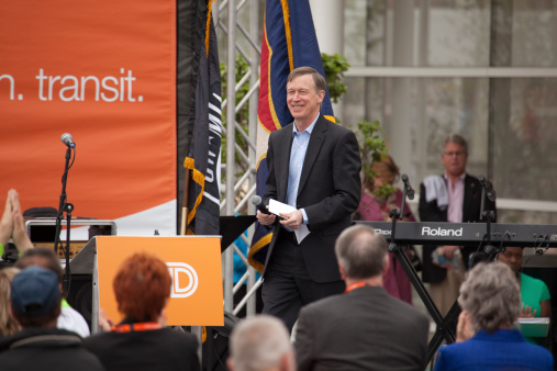 Denver, Colorado, USA - May 9, 2014: A smiling Colorado Governor John Hickenlooper walks across the stage as crowds of people gather to listen at the grand opening of the Union Station Transit Center in downtown Denver.
