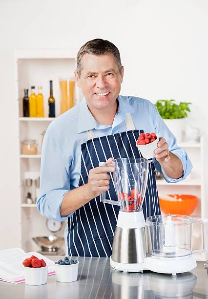 istock Mature Man Pouring Raspberries Into  Blender While Making Smoothie/ Dessert 489699033