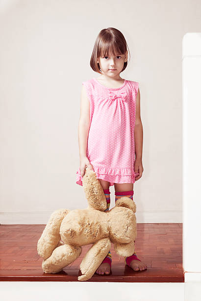 маленькая девочка стоит и держит плюшевый медведь - child little girls shy standing стоковые фото и изображения