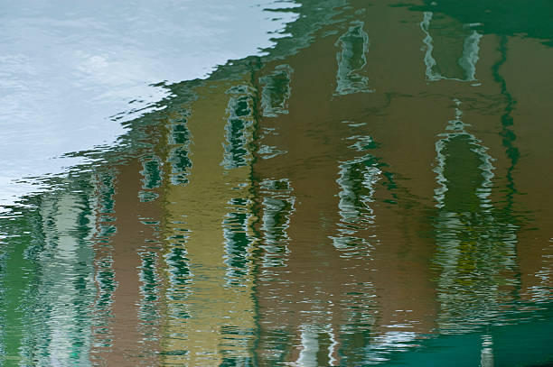 the typical colored houses reflected on one of the canals of Burano
