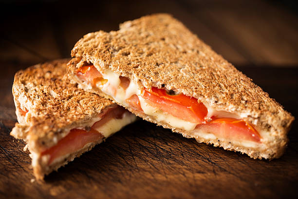 Cheese and Tomato toasted sandwhich Cheese and Tomato toasted sandwich against rustic wood. toasted sandwich stock pictures, royalty-free photos & images