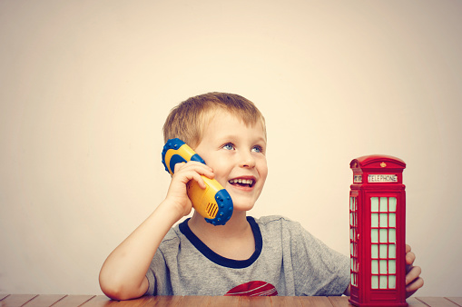 Boy talking on the phone and vintage british red telephone booth