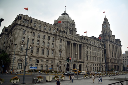 Shanghai, China - July 25, 2015: People walking on The Bund, a scenic waterfront area in central Shanghai. It is one of the most famous tourist destinations in Shanghai and houses buildings of various architectures.