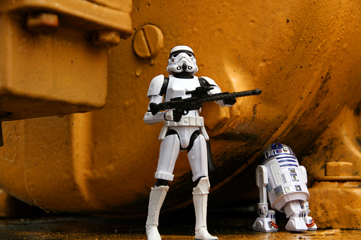 Vancouver, Canada - August 30, 2015: R2D hiding from a Stormtrooper. Both models are from the Star Wars film franchise and are against weathered metal on Granville Island in Vancouver. The toys are part of the Black Series, from Hasbro.