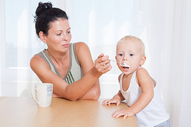 istock Beautiful young mother feeding his little son with yogurt 489732370