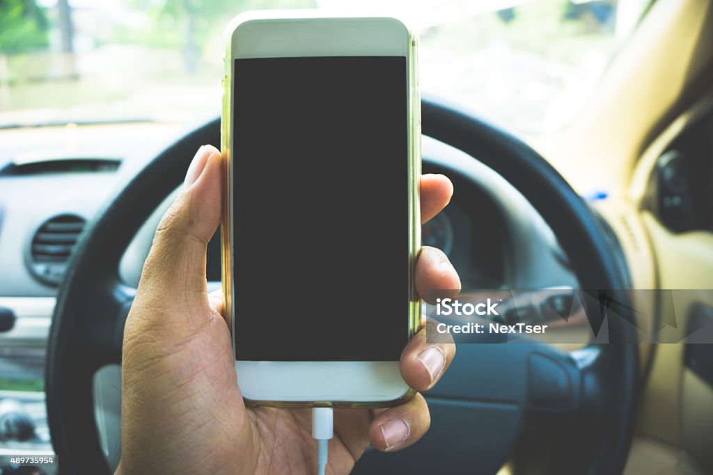 using a smartphone while driving a car man using a smartphone while driving a car with a filter effect Driving Stock Photo