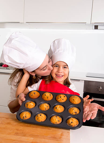 istock mother with daughter wearing cook hat presenting muffin set 489738422