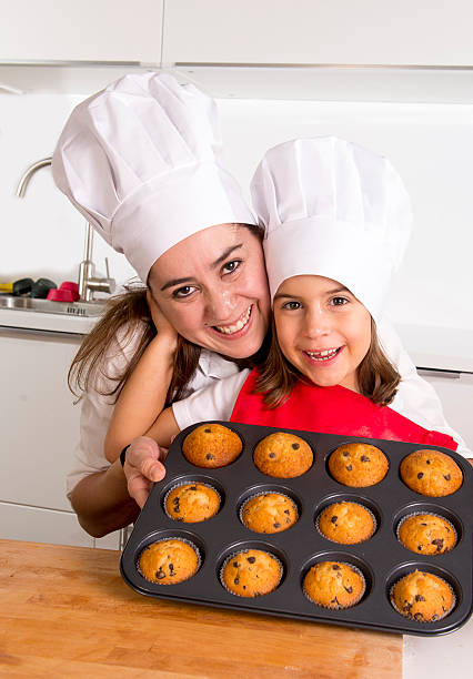 istock mother with daughter wearing cook hat presenting muffin set 489752622