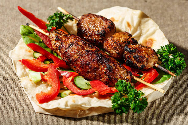 Shish kofte kebab Shish kofte (kofta kebab) with vegetables and herbs on naan or lavash or pita flatbread halal stock pictures, royalty-free photos & images