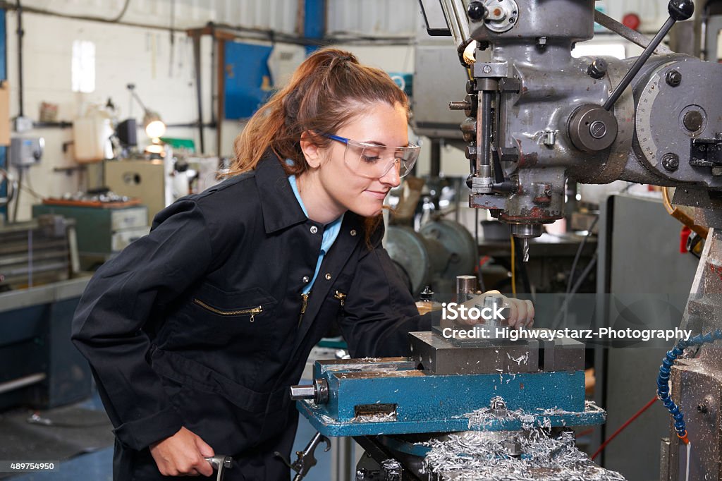 Aprendiz mujer ingeniero trabajando en la fábrica de taladro - Foto de stock de Chica adolescente libre de derechos