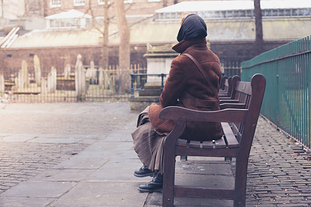 istock woman sitting on bench in graveyard 489755462