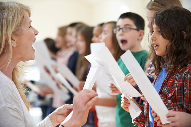 istock Children In Singing Group Being Encouraged By Teacher 489755578