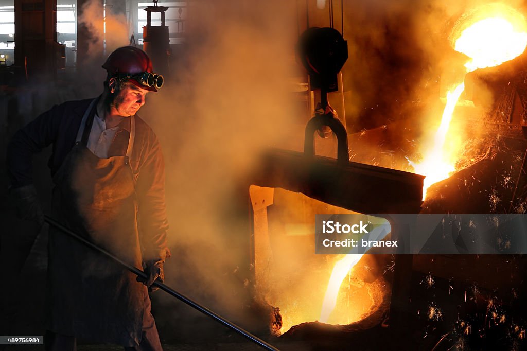 Hard work in the foundry Hard work in the foundry, worker controlling iron smelting in furnaces, too hot and smoky working environment Steel Worker Stock Photo