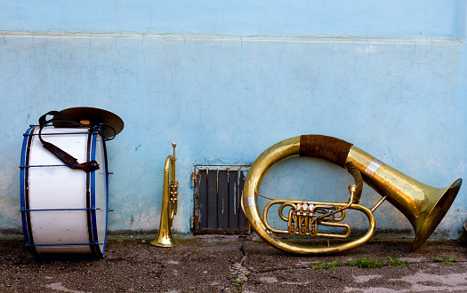 Set of brass instruments left close to blue facade for a short break in a street music performance 