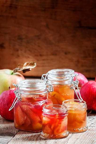 Autumn apple jam ripe red apples in jars on an old wooden table, selective focus