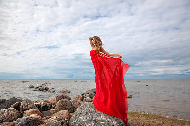 istock woman with red fabric on sea beach 489763628