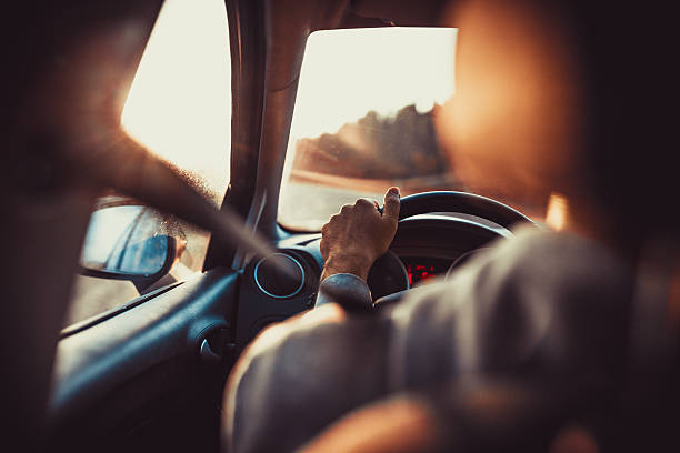 Man driving car Man driving car, hand on steering wheel, looking at the road ahead,sunset. buckle photos stock pictures, royalty-free photos & images
