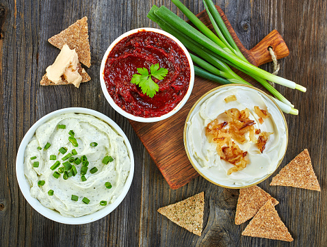Various dip sauces and bread crackers on wooden table, top view