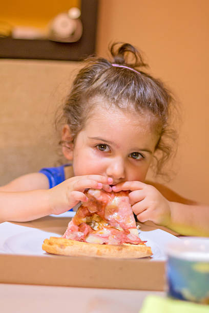 istock curly little girl eating pizza 489768090