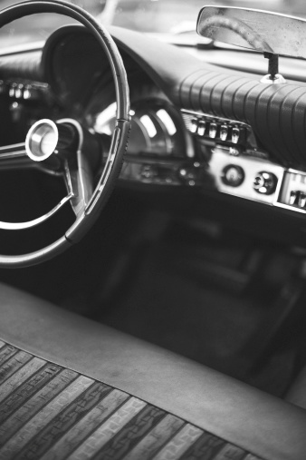 Vintage car steering wheel, dash board and interior, of a 1962 Chrysler Newport. Some grain added in post processing to give vintage look. Shot with a 50mm lens at f/1.6, short depth of field.