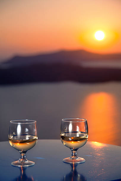 istock Two glasses of white wine on a sea sunset background. 489772927