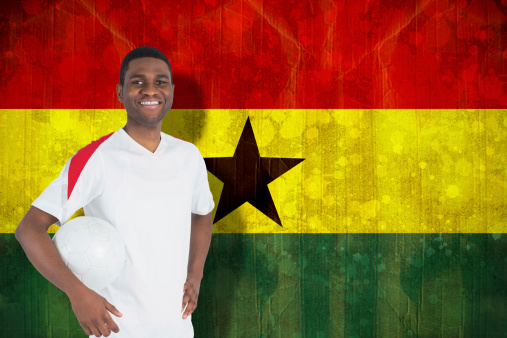 Handsome football fan looking at camera against ghana flag in grunge effect