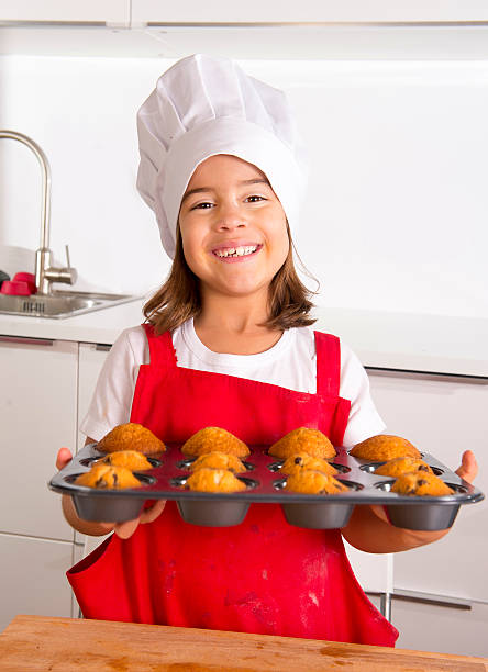 istock happy proud female child presenting muffin cakes learning baking 489778770