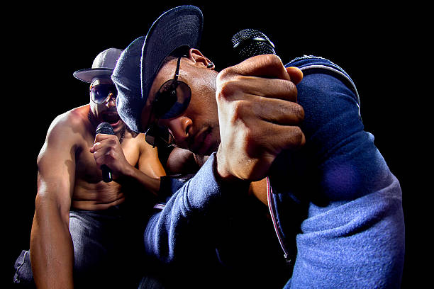 Rappers Hip Hop Concert Rappers having a hip hop music concert with microphones.  They look arrogant during their music performance.  The men are wearing trendy hip hop clothing while showing off their muscles.  The singers are african american on a black background. african american culture photos stock pictures, royalty-free photos & images