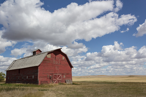 red barn with blue sky and fluffy clouds in summertime