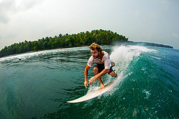 Surfer Races Along A Perfect Wave A young male surfer races close to the camera. Mentawai Islands stock pictures, royalty-free photos & images