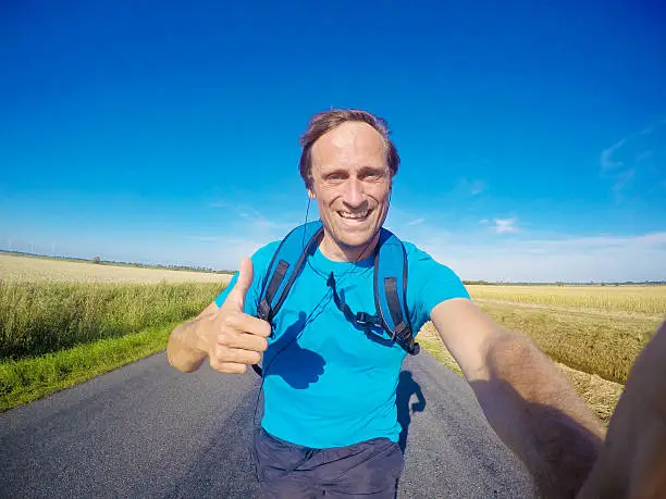 A happy male jogger, jogging  on a rural tarr road in Schleswig-Holstein, Germany. GoPro Hero 4 black edition image.