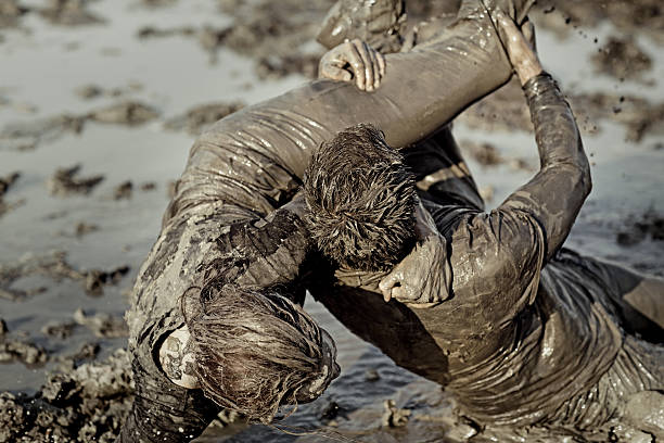 istock Young couple wrestling during a mud run 489802246