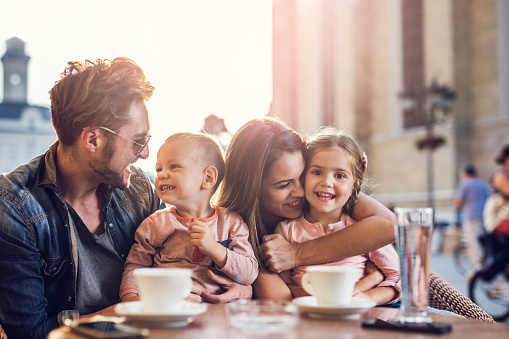 Happy parents enjoying with their children in a cafe and having fun with them.