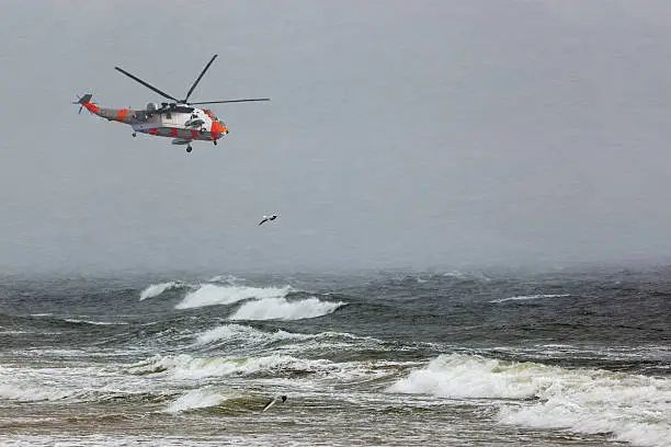 A helicopter rescue mission in difficult stormy weather at sea.