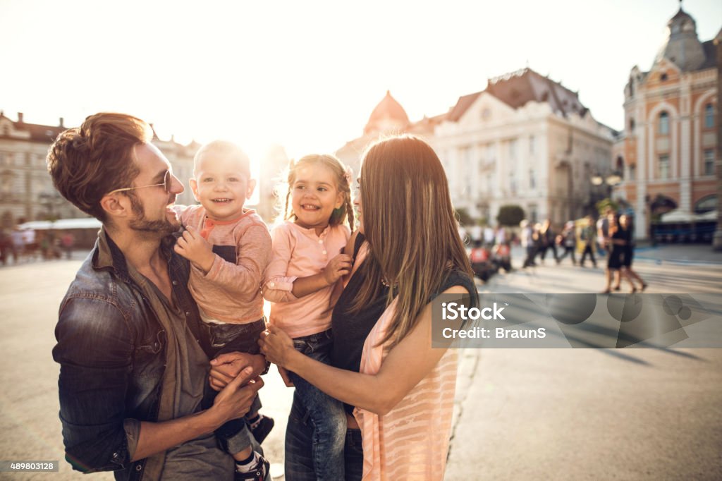 Young smiling family spending a day in the city. Young parents holding their children and enjoying with them in the city. 2015 Stock Photo