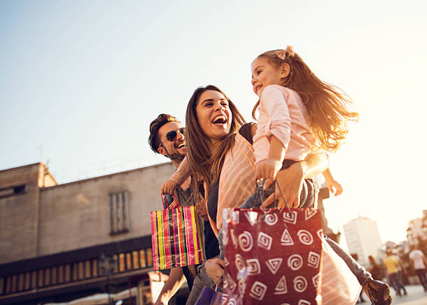 Below view of young cheerful family in shopping. Low angle view of cheerful family having fun during a shopping day in the city. merchandise stock pictures, royalty-free photos & images
