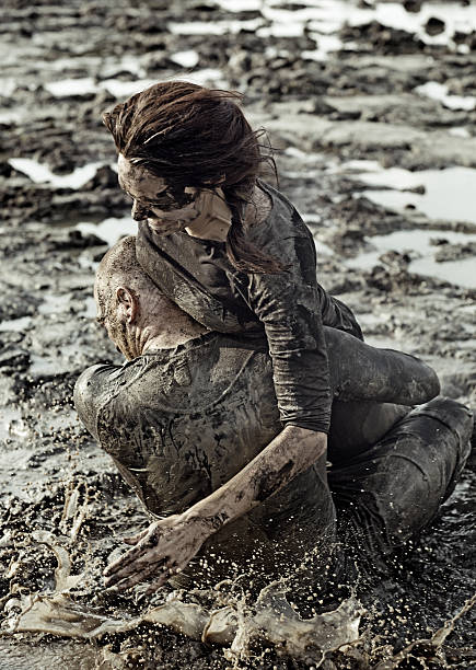 istock Young couple wrestling during a mud run 489803312