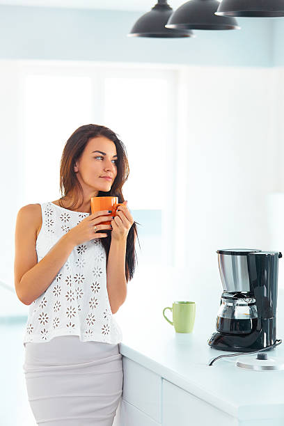 istock Woman holding a cup of coffee in her kitchen 489803384