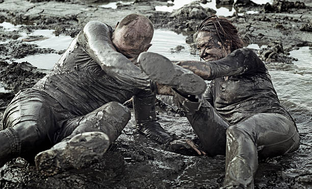 istock Young couple wrestling during a mud run 489803506