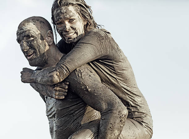 istock Shaved man carrying young female during a mud run 489804186