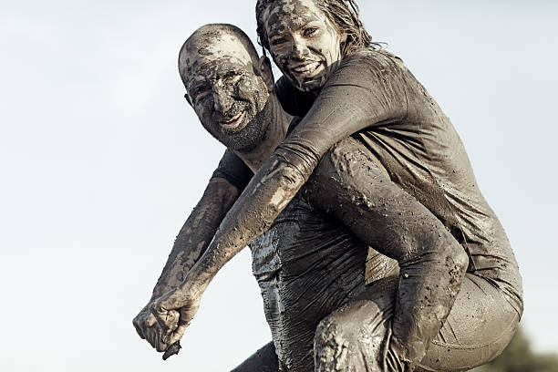 istock Shaved man carrying young female during a mud run 489804230