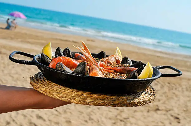 a typical spanish paella with seafood in a paellera, the paella pan, on the beach
